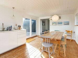 Une cuisine spacieuse avec une grande table en bois, des armoires blanches et une porte-fenêtre coulissante donnant sur un balcon.