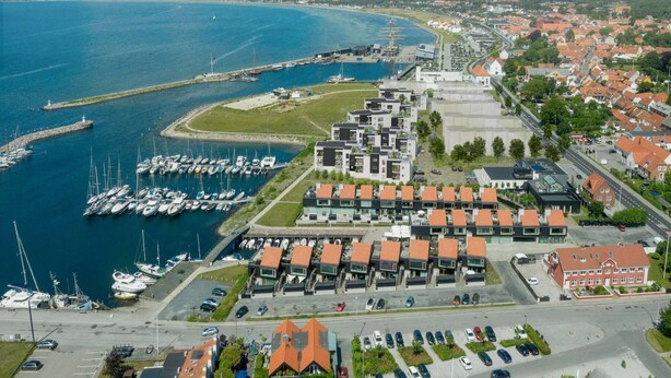 An aerial view of a coastal town with a marina, modern buildings, and a red-roofed structure. - 4 Person Holiday Home in Ebeltoft-by Traum (Ebeltoft)