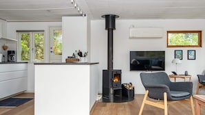 A modern living space with a kitchen, a central island, a fireplace, and a seating area with a TV. - 4 Person Holiday Home in Ebeltoft-by Traum (Ebeltoft)