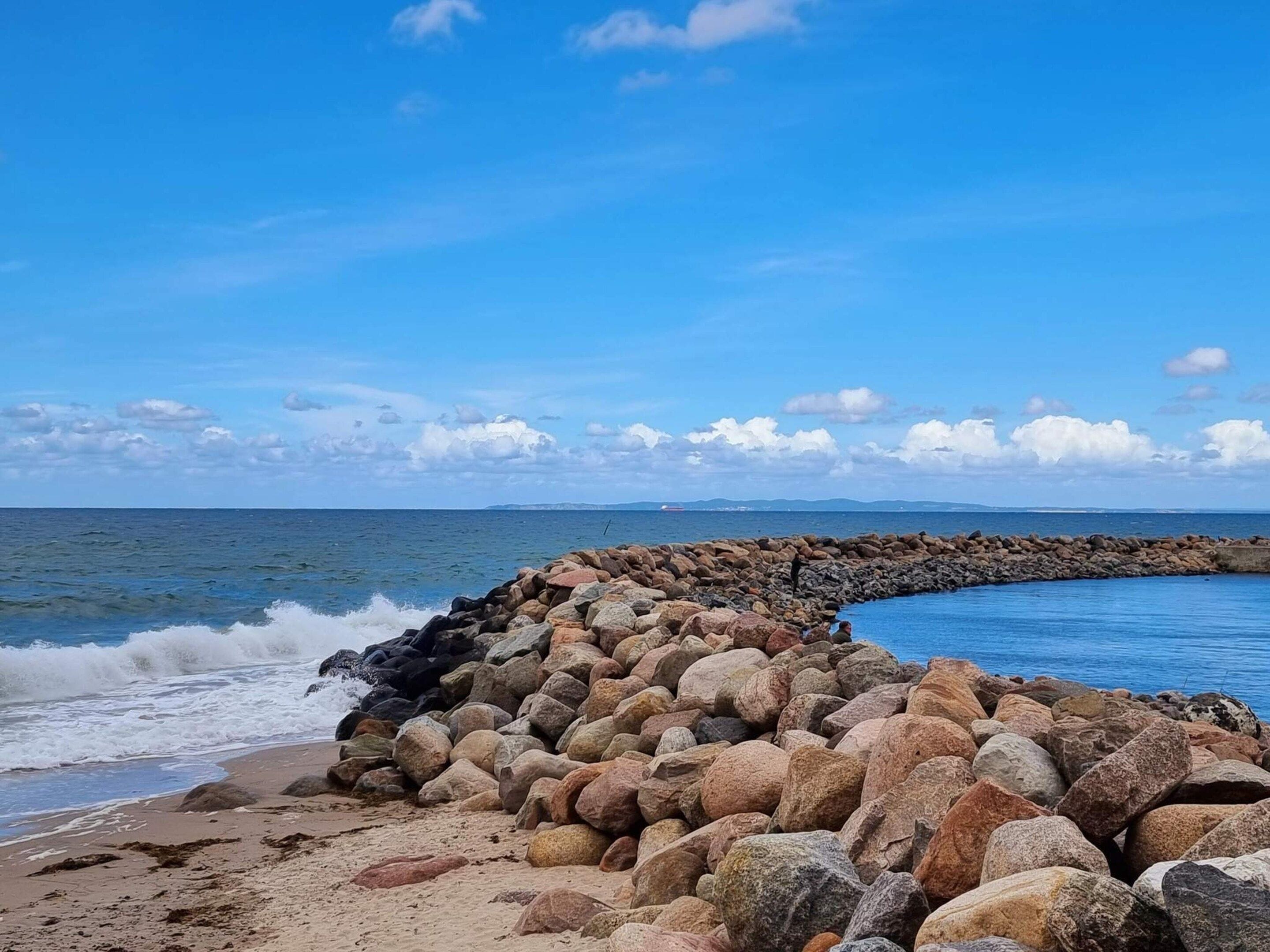A rocky shoreline with waves crashing against a stone barrier.