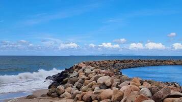 A rocky shoreline with waves crashing against a stone barrier.