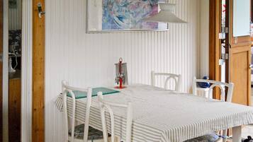 A dining area with a white table, striped tablecloth, and white chairs.