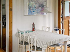 A dining area with a white table, striped tablecloth, and white chairs.
