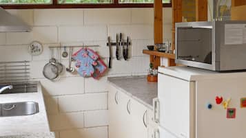 A kitchen with white cabinets, a microwave, and various utensils hanging on the wall.
