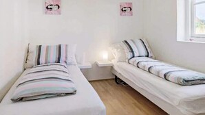 A small, clean room with two single beds, a nightstand, and a window. - 8 Person Holiday Home in Lokken-by Traum (Lokken)