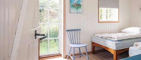 A room with a bed, a chair, a window, and a painting on the wall.