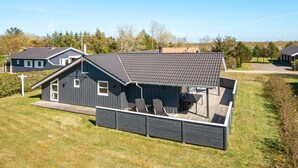 A modern house with a large deck, a covered outdoor seating area, and a view of wind turbines in the background. - 4 Star Holiday Home in Hemmet (Hemmet)