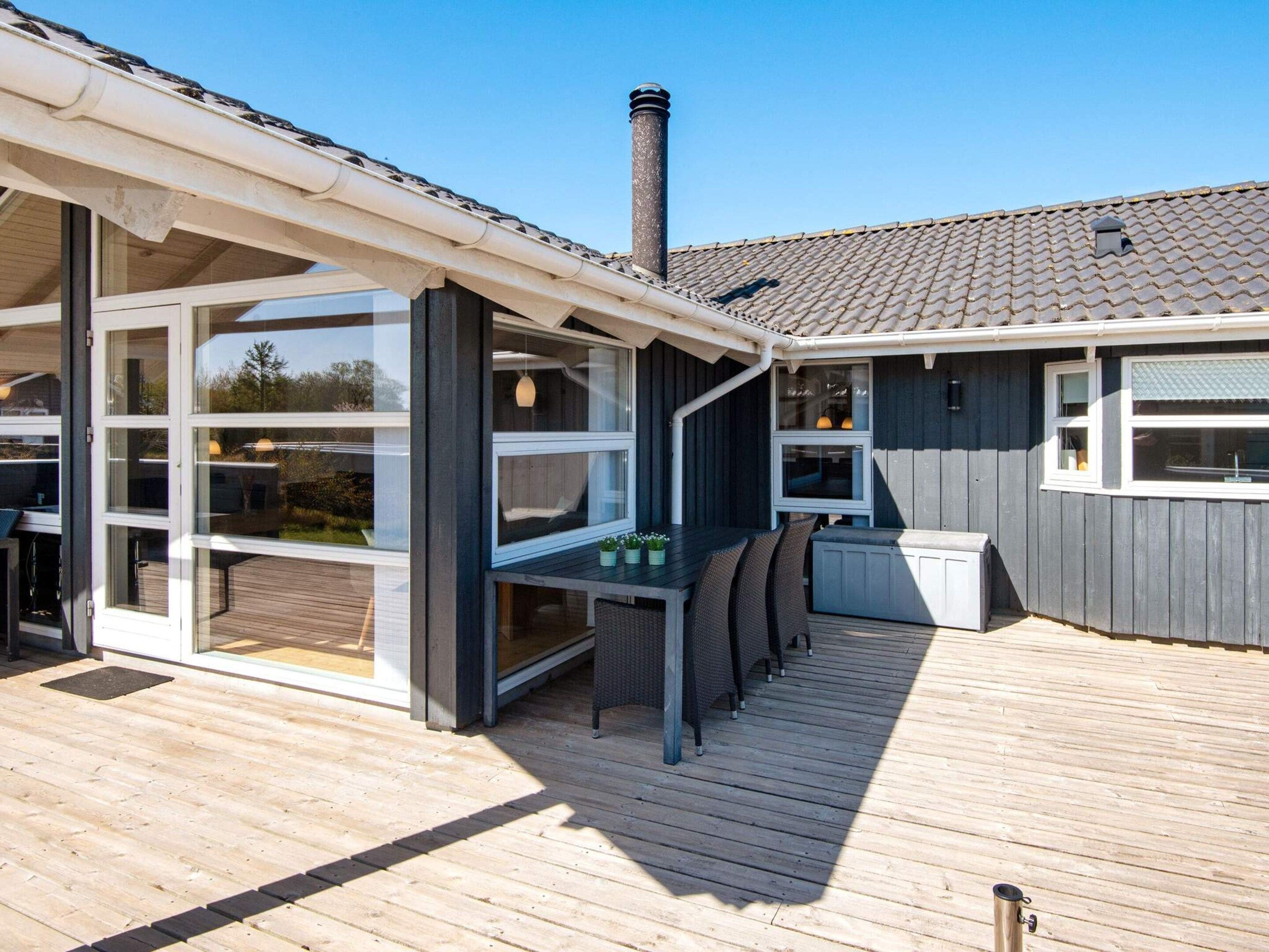 Ett takförsett utomhusområde med ett trädäck, ett bord med stolar och en skorsten.