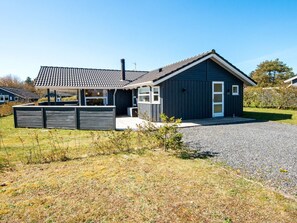 Et moderne hus i to etager med mørk facade, et tegltag og en veranda.