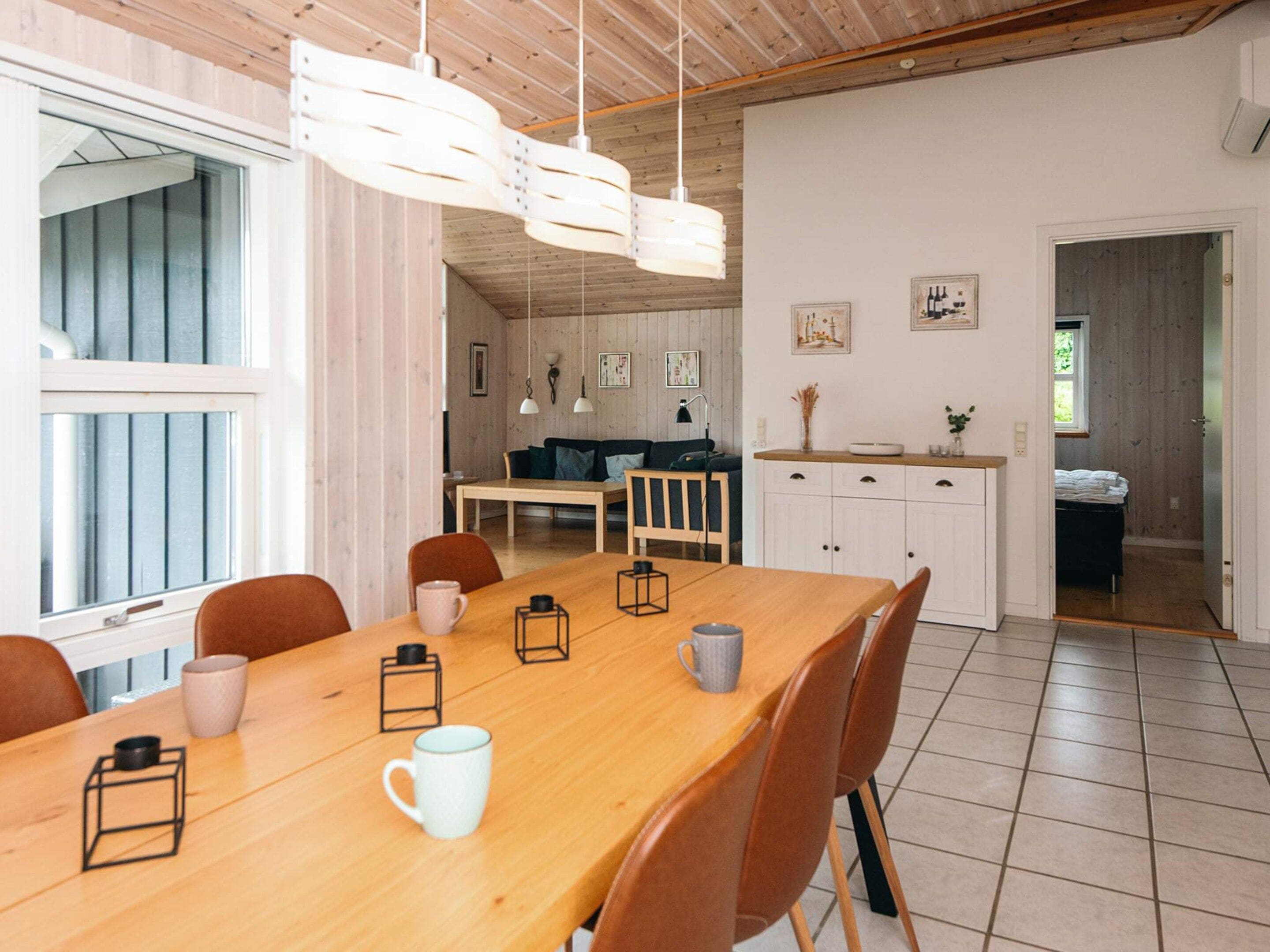 A dining area with a wooden table, chairs, and hanging pendant lights.
