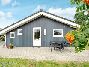 A grey building with a white door, windows, and a small outdoor seating area with a table and chairs.