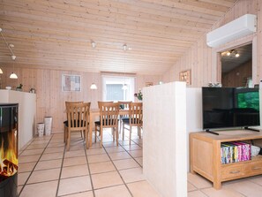 Ein gemütliches Blockhaus-Interieur mit einer Holzespeiseecke, einem Fernseher und einem Bücherregal.