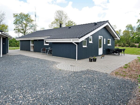 A modern building with a dark exterior, a flat roof, and a gravel driveway.