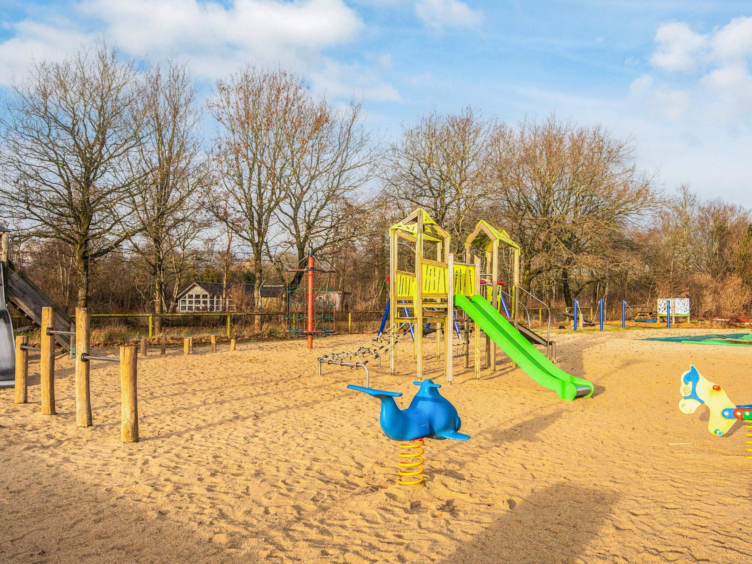 A playground with a slide, climbing structures, and a blue and yellow toy.