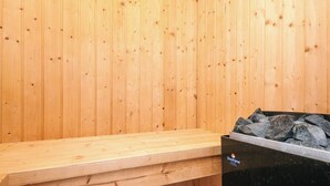A sauna room with wooden walls, a bench, and a black heater. - 4 Star Holiday Home in Oksbol (Oksbol)