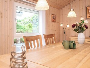 A wooden interior with a dining table, chairs, a vase with flowers, and pendant lights. - 4 Star Holiday Home in Oksbol (Oksbol)