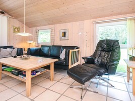Una habitación con paneles de madera, un sofá, una silla, una mesa y una lámpara de pie.