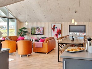 A spacious living area with a large window, a dining table, and a kitchen counter.