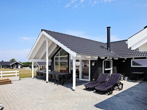 A modern house with a covered patio, outdoor seating, and a chimney.