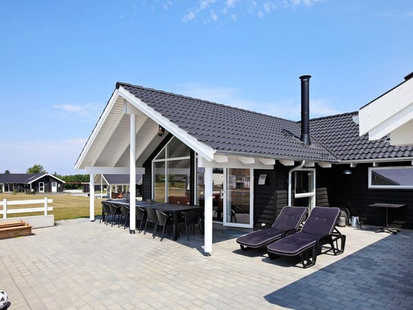 A modern house with a covered patio, outdoor seating, and a chimney.