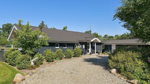 A two-story building with a gravel driveway leading to a covered patio area.