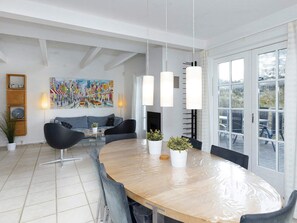 A modern dining area with a wooden table, grey chairs, pendant lights, and a cityscape painting on the wall. - 5 Star Holiday Home in Blokhus (Blokhus)