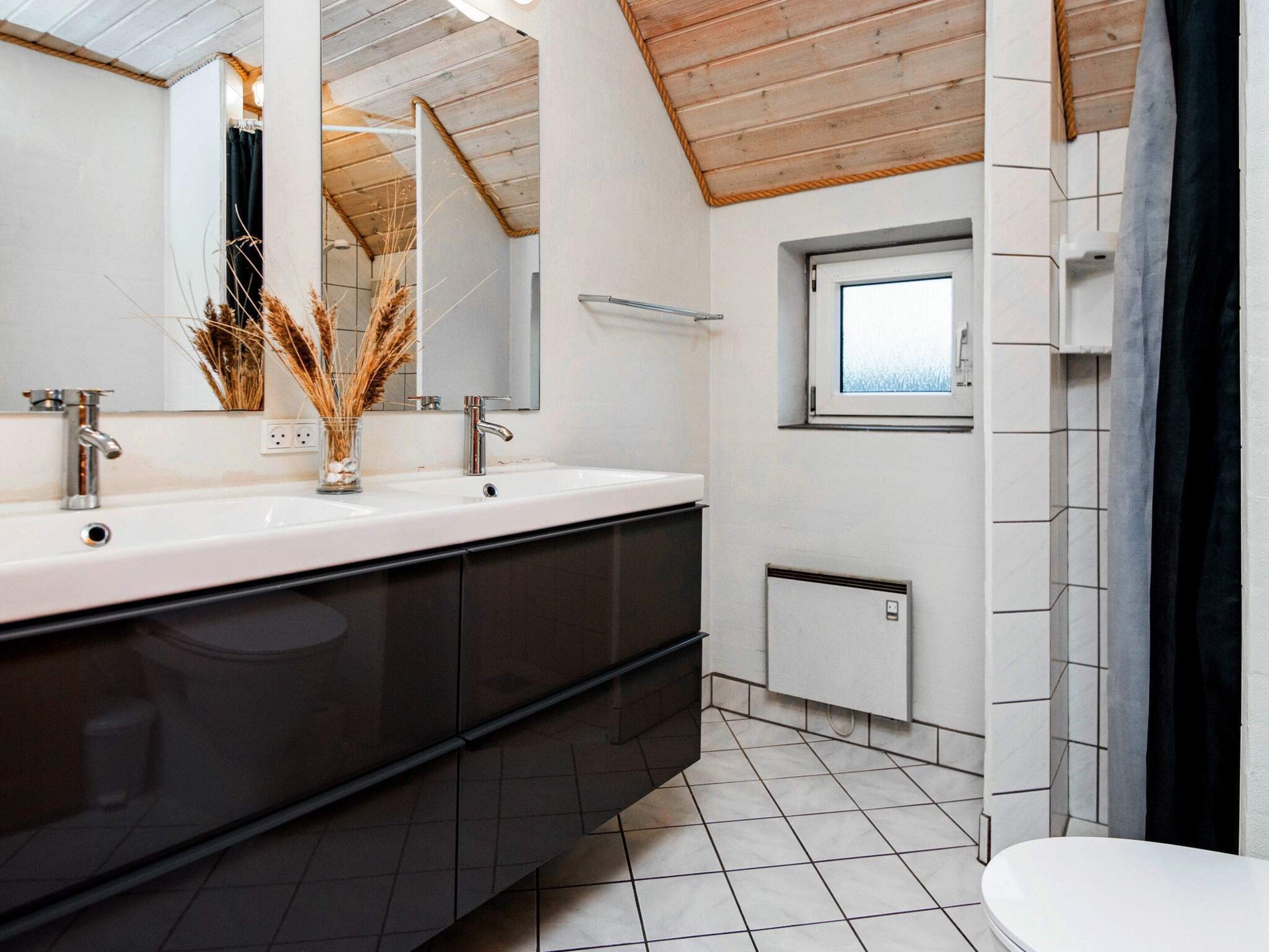 Een moderne badkamer met een ruime wastafel, twee wasbakken, een raam en een radiator.