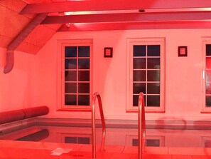 A red-lit room with two windows and a bench.