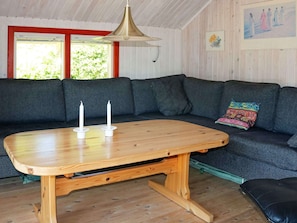 A wooden table with two candles, a dark grey sofa, and a colorful cushion.