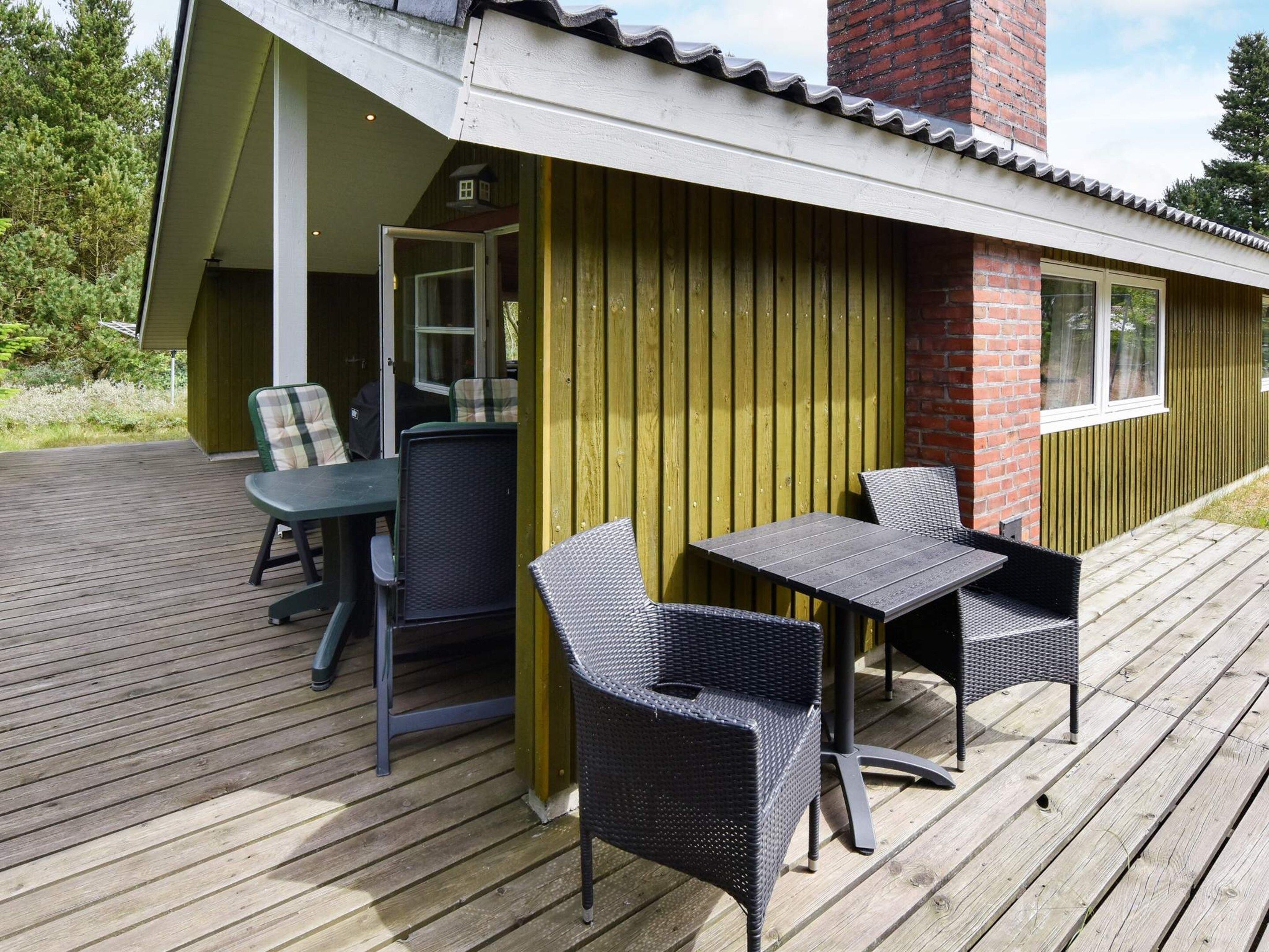 A wooden deck with outdoor furniture, including chairs and a table.