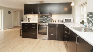 A modern kitchen with dark cabinets, a stainless steel oven, and a microwave. - 5 Person Holiday Home in Vig (Vig)