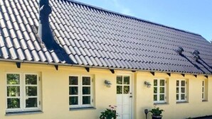 A yellow building with a tiled roof, multiple windows, and potted plants. - 5 Person Holiday Home in Vig (Vig)