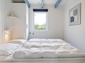 Un dormitorio con cama, ventana, estante montado en la pared y un cuadro enmarcado.