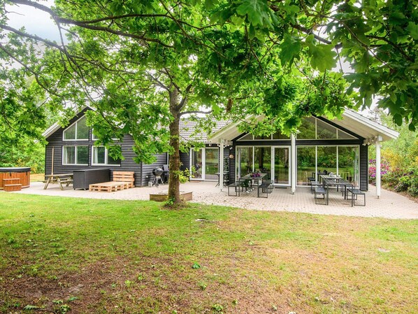 Une maison moderne dotée d’un patio, d’un jacuzzi et d’un espace salon extérieur abrité.