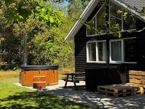 A cabin with a hot tub, picnic table, and wooden benches.