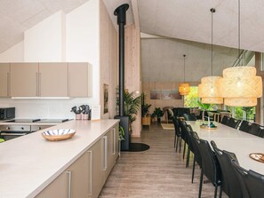 Une cuisine moderne dotée d’un grand îlot central, d’un coin repas avec une grande table et offrant une vue sur l’extérieur.