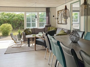 A cozy living room with a sofa, chairs, a dining table, and a large window. - 4 Star Holiday Home in Orsted (Ørsted)