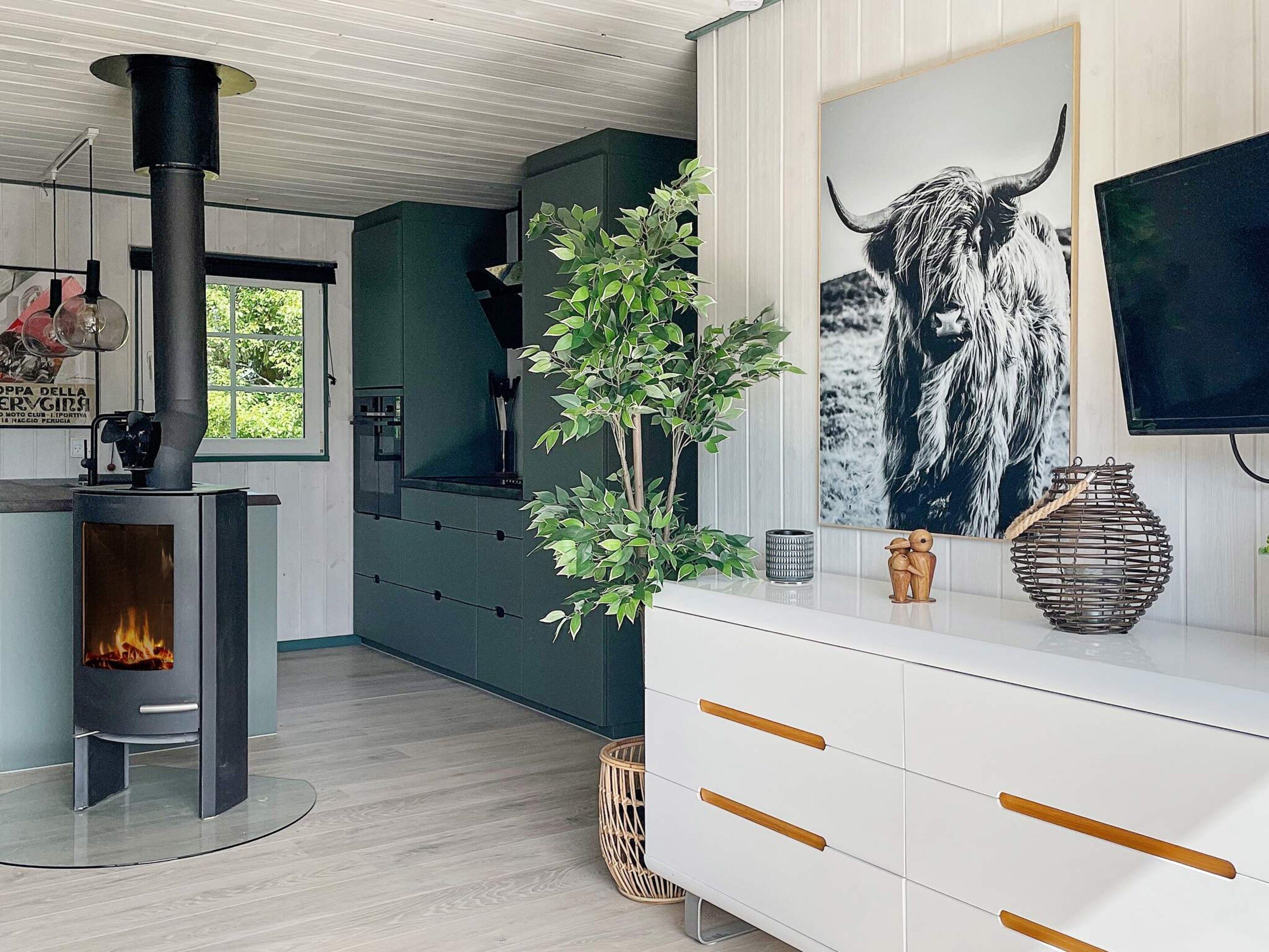 Una cocina moderna con estufa de leña, un ventanal grande y un cuadro decorativo de un toro.