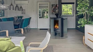 Uma sala de estar moderna com lareira, um espaço de refeições com cadeiras e uma janela ampla.