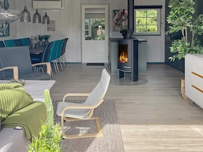 A modern living room with a fireplace, a dining area with chairs, and a large window.