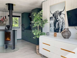 A modern kitchen with a wood-burning stove, a large window, and a decorative plant.