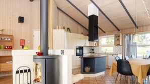 A modern kitchen with a central wood stove, a dining area with a table and chairs, and a kitchen island with a sink and countertop.