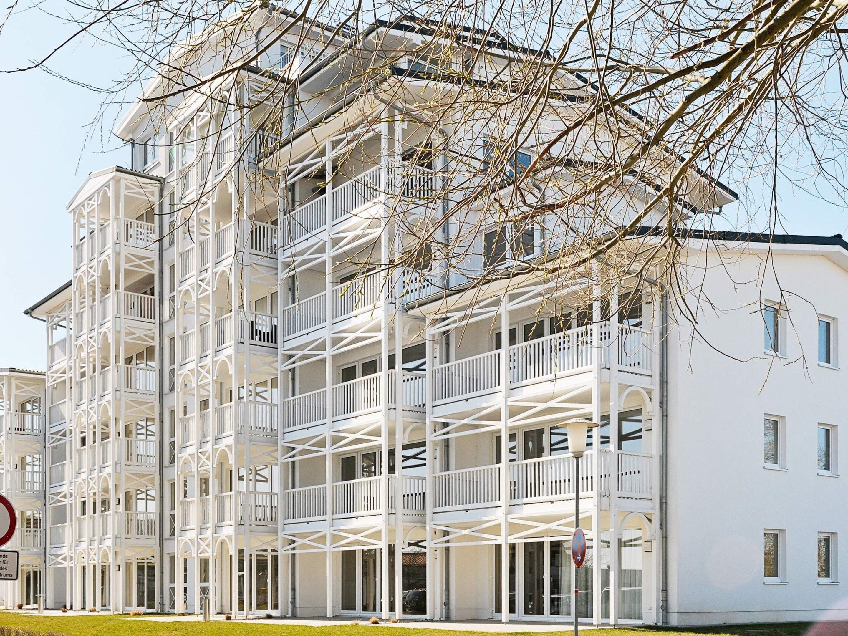 A multi-story building with balconies and a white facade.