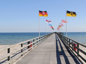 A wooden pier extending into the sea with multiple flags on poles. - Holiday Home in Grossenbrode (Grossenbrode)