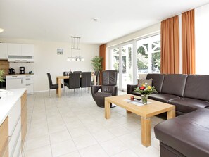 Un salon moderne avec un canapé en cuir marron, une table basse en bois et un coin repas comprenant une table et des chaises.