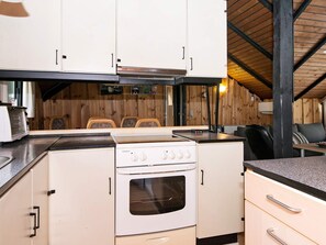 A compact kitchen with a stove, oven, and cabinets. There is a dining area with a table and chairs.