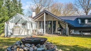 Een huis met een glazen serre, een vuurkorf en een overdekt terras.