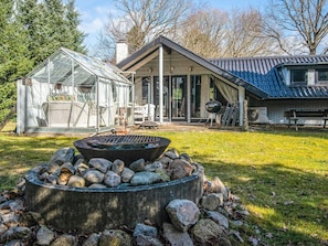 A house with a glass greenhouse, a fire pit, and a covered patio area. - Spacious Holiday Home in Ansager near Lake (Ansager)