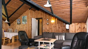 Een knus vertrek met een houten plafond, een bank, een tafel en een stoel.