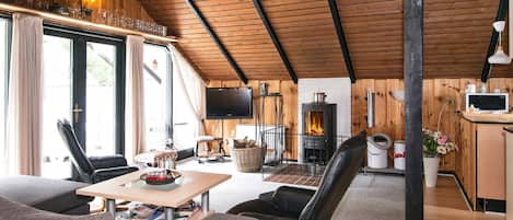 A cozy living room with a fireplace, a television, and a dining area with a table and chairs.